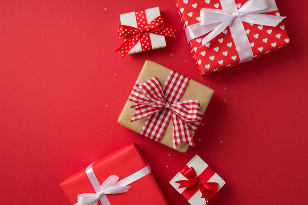 俯视图照片的情人节装饰工艺纸礼盒与方格丝带蝴蝶结亮片和礼物在孤立的红色背景与空白空间图片下载