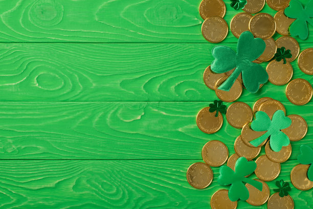 顶视图照片的圣帕特里克节装饰绿色三叶草三叶草形状的纸屑和许多金币在孤立的绿色木制桌子背景copyspace图片下载