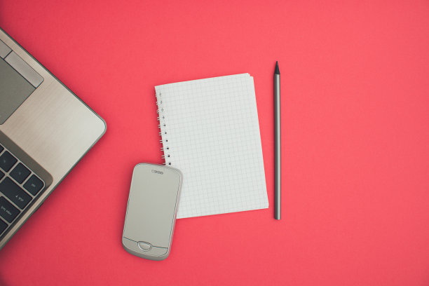 商务A6笔记本线材装订模拟空白模板设计思路。灰色笔记本电脑，手机和铅笔模型对柔和的粉红色背景。复制消息布局的空间模板设计。图片下载