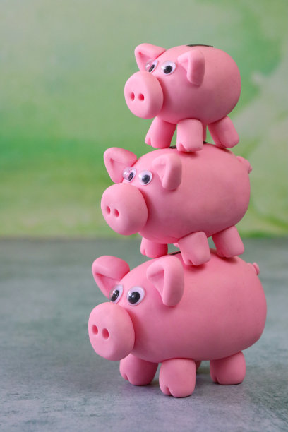 三个模型储蓄罐堆叠的特写图像，重点前景，斑纹绿色背景，侧面视图，家庭理财和储蓄概念图片下载