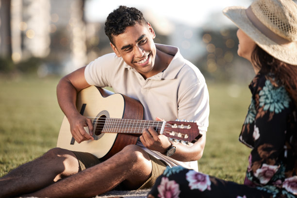 这张照片拍摄的是一个年轻人在和女朋友野餐时弹吉他图片下载