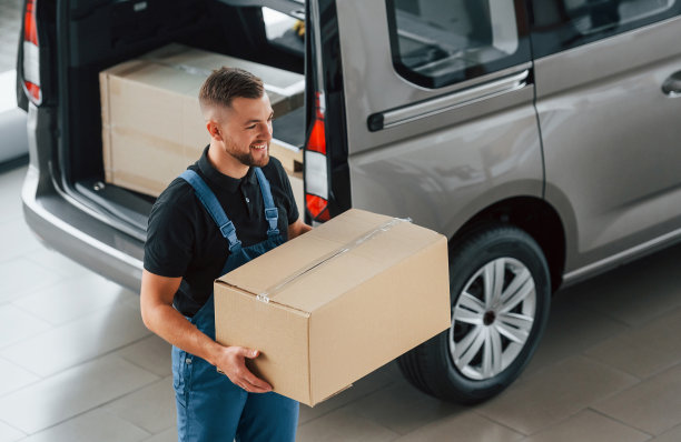 走路，手里拿着盒子。穿制服的送货员开着车，带着订单待在室内图片下载