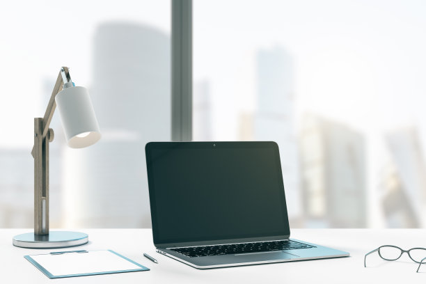 近距离的创意设计师办公室桌面与模拟的地方黑色笔记本电脑屏幕，台灯，用品和其他项目。模糊的城市视图背景。3 d渲染。图片下载