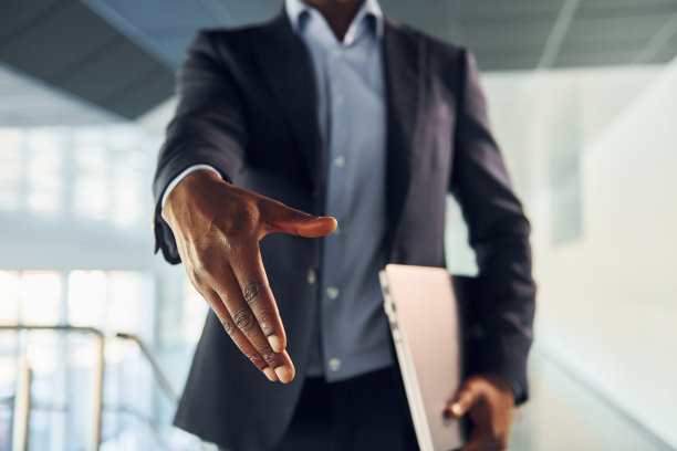 握手的姿势。穿着黑色西装的年轻非裔美国商人在室内图片下载
