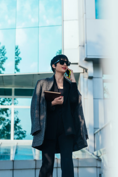 有吸引力的年轻女商人在办公大楼外打电话图片下载