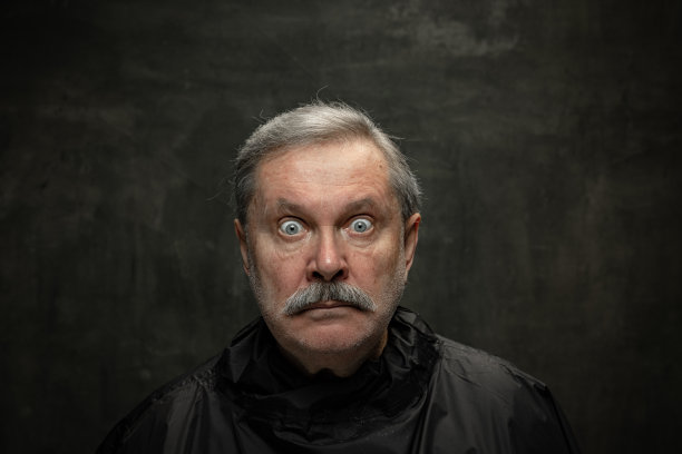 震惊的资深男子的肖像看着相机与大眼睛孤立在黑暗的复古背景。情感观念、时尚、美、自我再造图片下载