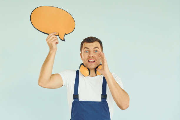 脖子上戴着大耳机。一个男人站在画室里，手里拿着空白的牌子图片下载