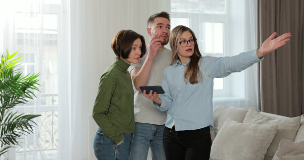 女房地产经纪人展示年轻夫妇使用平板电脑的公寓计划的特写。购房的概念。图片下载