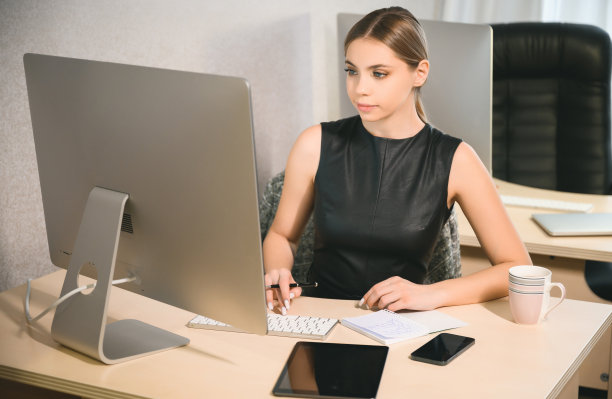 头部照片愉快快乐的年轻女性自由职业者在办公室的电脑上工作。有吸引力的女商人在线学习，使用笔记本电脑软件，网上冲浪信息或在网上商店购物图片下载