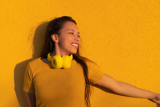 一个脖子上戴着黄色音乐耳机的拉丁女人的肖像，看着一边。图片下载