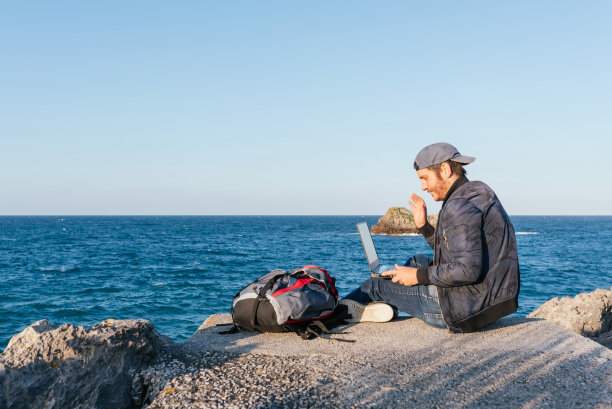 在大海前使用电脑的人。图片下载