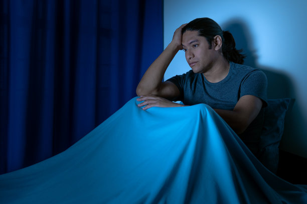 抑郁的人晚上在床上坐起来，他因失眠而睡不着图片下载