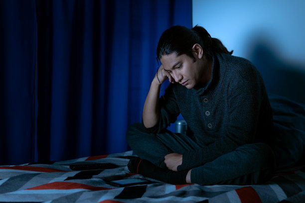 抑郁的人晚上在床上坐起来，他因失眠而睡不着图片下载