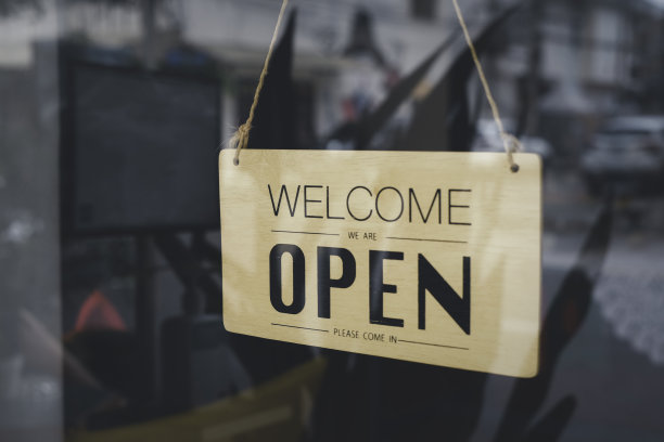 商店玻璃窗后模糊的图片，上面写着“欢迎光临，我们是开放的”，带有阳光效果。商务服务和餐饮理念。图片下载
