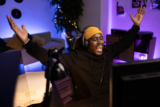 视频玩家在赢得射击比赛后通过耳机举手向团队喊话。男人在胜利的喜悦中，黑暗的房间被led灯照亮图片下载