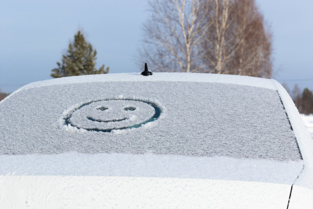 在冬天阳光明媚的日子里，一辆汽车的后车窗上画着一张笑脸。有选择性的重点。图片下载