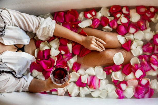 性感的女性身体在黑色性感内衣躺在复古浴与水玫瑰花瓣图片下载