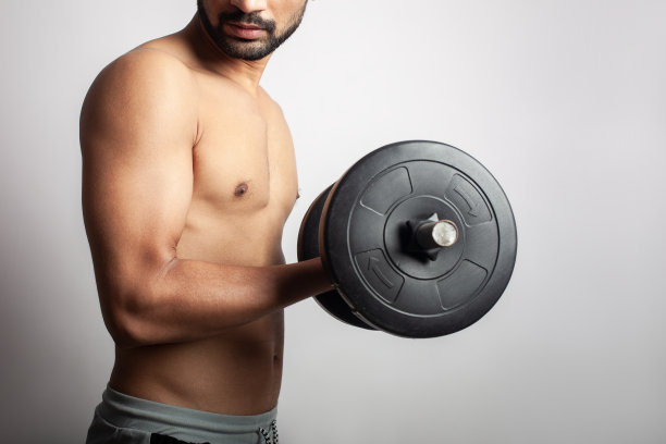 在白色的背景下进行二头肌卷曲锻炼的健美肌肉男图片下载