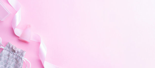 月经周期卫生杯。粉红色的缎带和月经杯。女性月经期。卫生卫生标语。在阴道内使用月经杯。图片下载