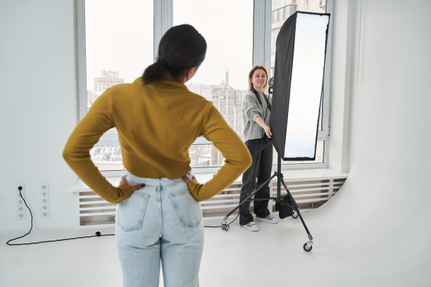 白人摄影师妇女拿着软盒子，而准备与多种族女孩的照片会议图片下载