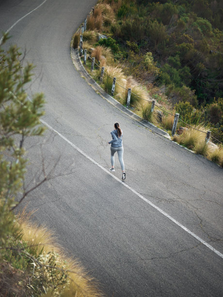 一个女人在山路上跑步的高角度镜头图片下载