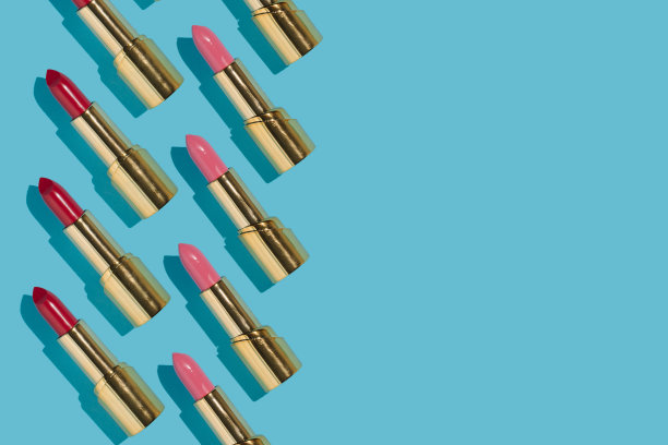 创意图案由红色和粉红色的金色唇膏在明亮的蓝色背景。复古的审美风格。最小平。新潮时尚的理念。图片下载