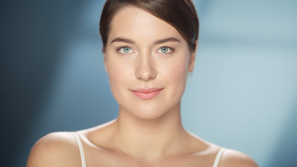 女性美丽的肖像。快乐的白人妇女与棕色的头发和浅绿色的眼睛摆姿势，触摸她的自然，健康的皮肤。柔软孤立背景下的健康护肤理念。关闭了。图片下载