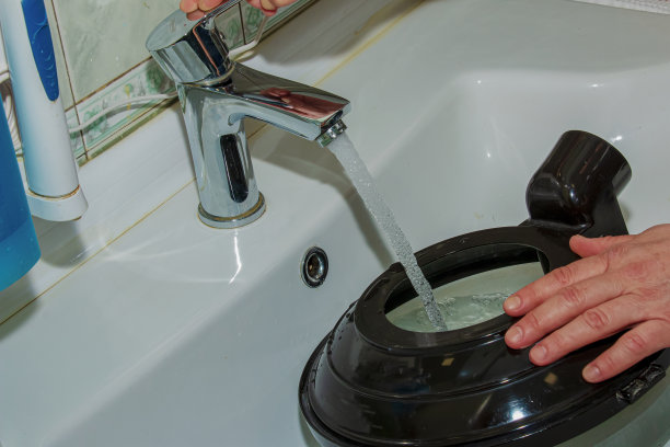 一名妇女将干净的水吸入水箱中，以便使用带有滤水器的清洗真空吸尘器。图片下载