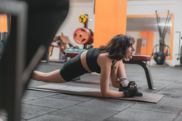 一名年轻女子在健身房的垫子上锻炼腹部肌肉。图片下载