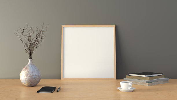 方形木制图片海报框架模型。木桌上放着咖啡、书、花瓶和笔记本。灰色的背景墙。图片下载