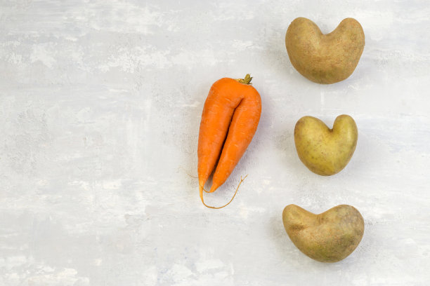 蔬菜或食物浪费的概念。丑陋的蔬菜:灰色混凝土背景上的心形土豆和胡萝卜。前视图。副本的空间。图片下载