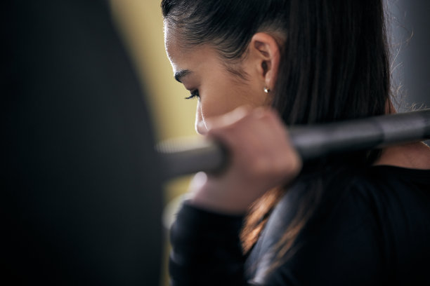 一名年轻女子在健身房用杠铃锻炼的后视镜照片图片下载