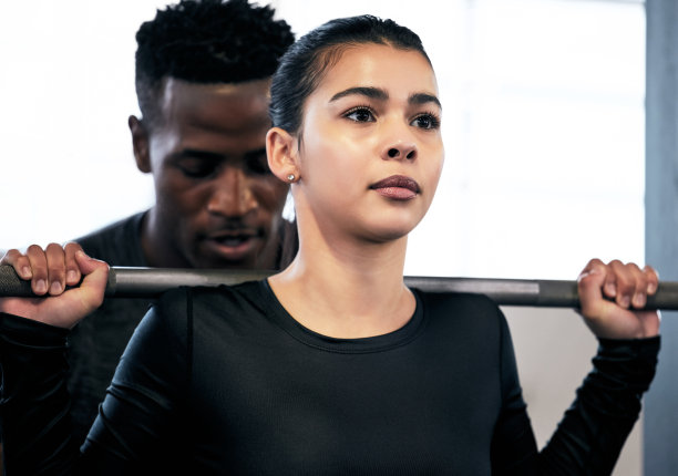 这张照片拍摄的是一对年轻的男女在健身房里用杠铃健身图片下载