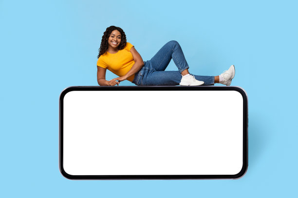 漂亮的黑人女士在巨大的智能手机上摆姿势，屏幕是空的图片下载