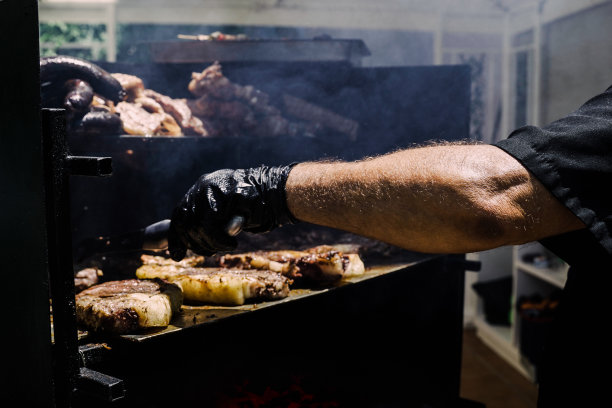 厨师在后院烧烤派对上做烤牛肉——专注于男人的手臂图片下载