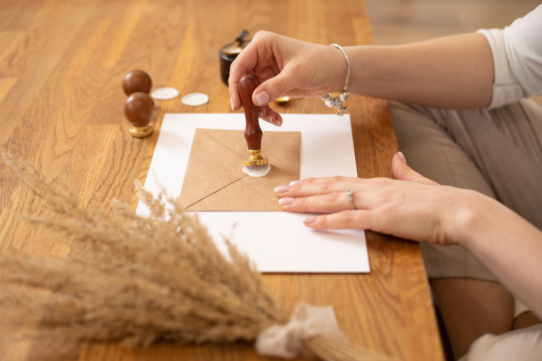 裁剪照片的妇女手制作证书卡片信封工艺，坐木桌，放封蜡印邮票图片下载