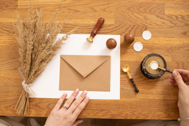 裁剪照片的女人坐着，制作生日明信片信封手工工艺，封蜡橡胶。前视图。加热蜡烛图片下载