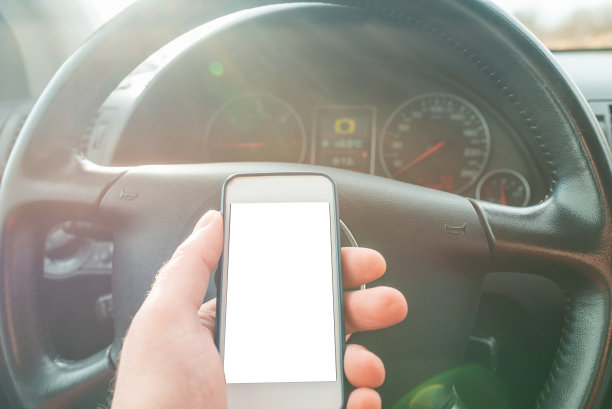 在春日的风景中，一名男子在车里使用空白屏幕的智能手机。为你的广告复制空间，模型。图片下载