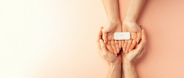 根验孕棒。女性手握阳性怀孕测试与丝带粉红色横幅背景。医疗保健妇科，孕产期产妇的观念。图片下载