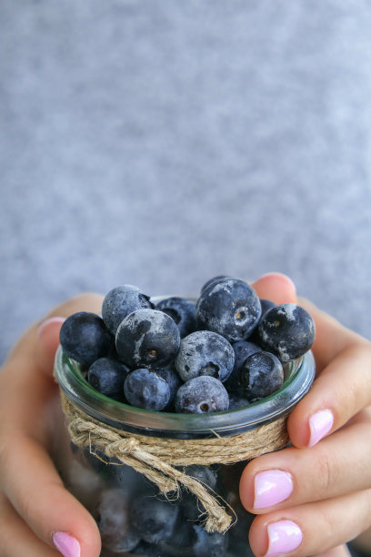 女人拿着盛着冷冻蓝莓水果的碗。收获的概念。女性收集浆果的手。健康饮食的概念。为冬天的素食者准备浆果图片下载