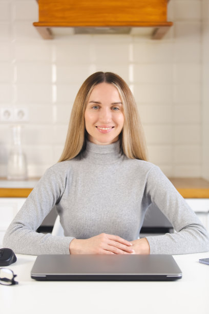 快乐的自由职业者女人看着镜头。美丽的年轻成年女性与笔记本电脑摆姿势与愉快的微笑。企业家在封锁期间准备在家工作图片下载