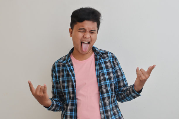 亚洲男人大声尖叫，举起双臂，举着喇叭或摆出摇滚的姿势图片下载