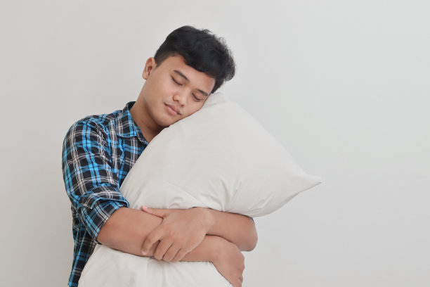 昏昏欲睡的亚洲男子抱着白色的枕头图片下载