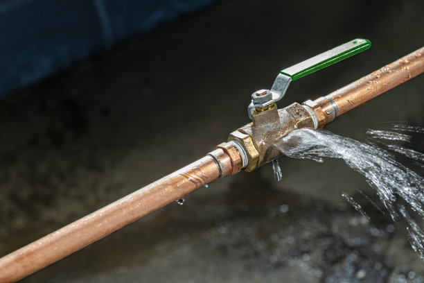 下面是一个破裂的黄铜球阀，水喷在地下室的地板上图片下载