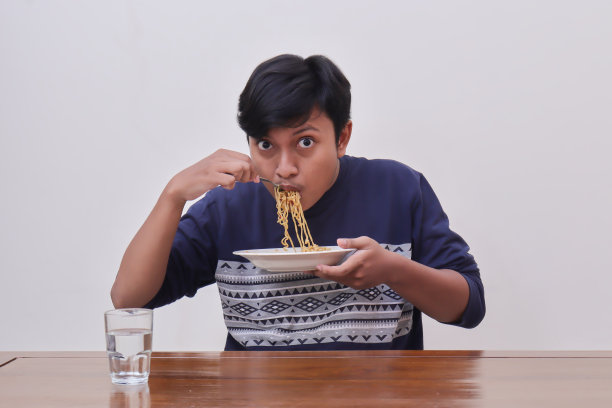 饥饿的亚洲男子吃方便面图片下载