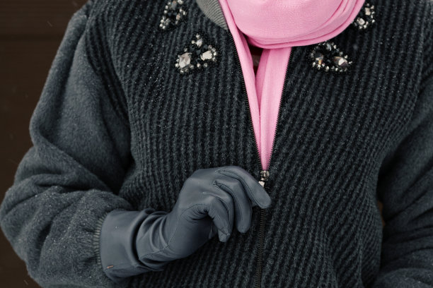 戴手套的女人在灰色针织夹克上系上拉链图片下载
