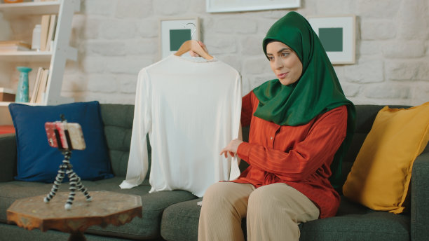 一位年轻的博主戴着头巾，通过视频会议向顾客介绍产品。图片下载