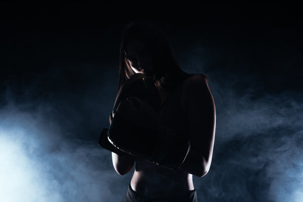 一个戴着拳击手套的女模特的剪影肖像，背景是白烟图片下载