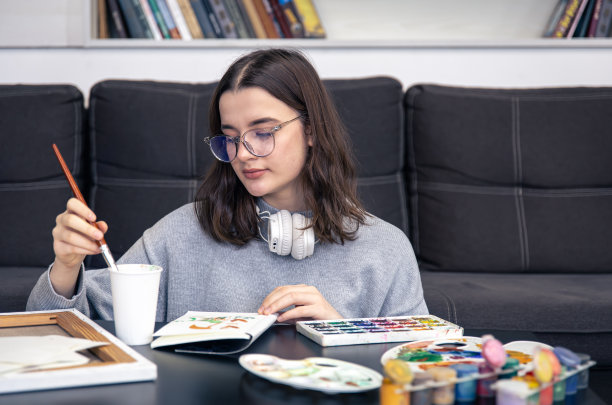 一位时髦的年轻女子在家里用颜料画画。图片下载