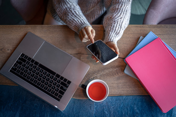 在咖啡馆里用笔记本电脑工作的女人喝着茶，俯视图。图片下载